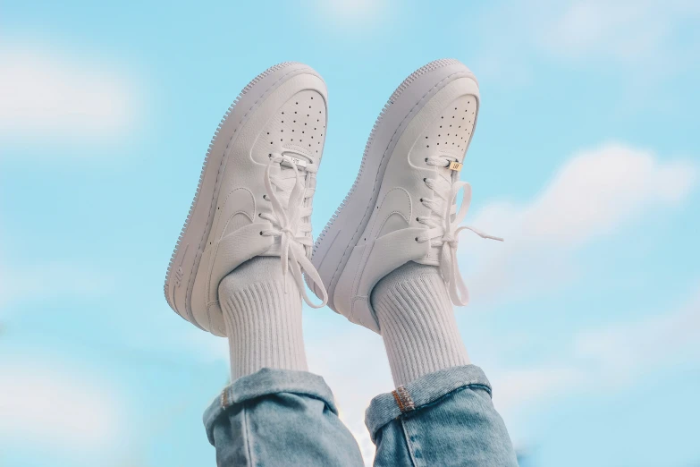 a person wearing white shoes and socks with their feet in the air