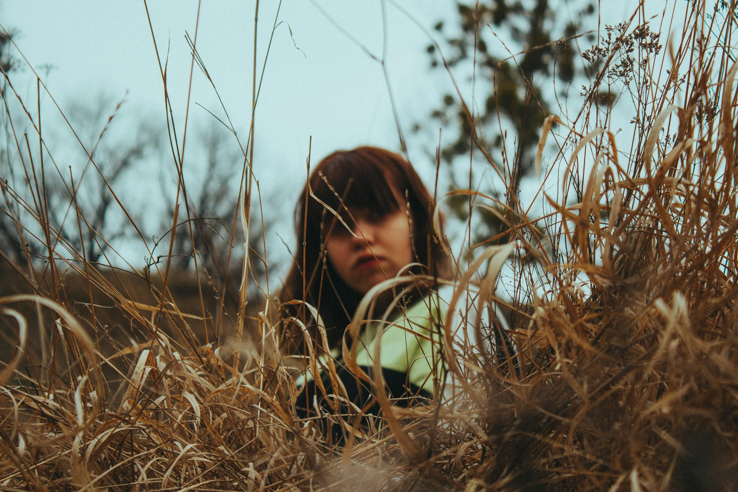 a girl peeking out from the tall grass