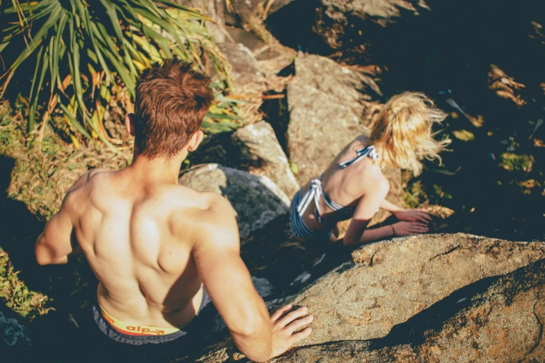 a guy and girl on rocks in the sun