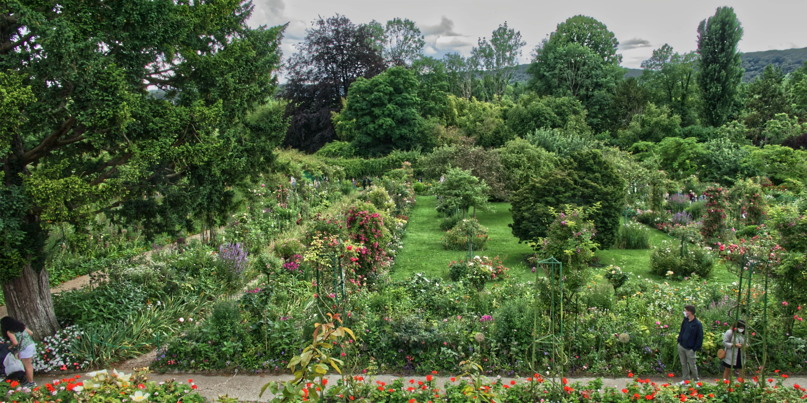 several people stand in a garden area with lots of flowers