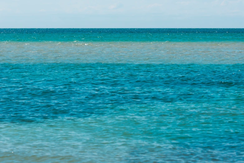 a body of water that is blue with the horizon in the background