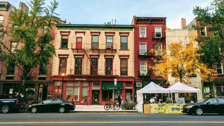 a row of brick buildings with cars parked on the sidewalk