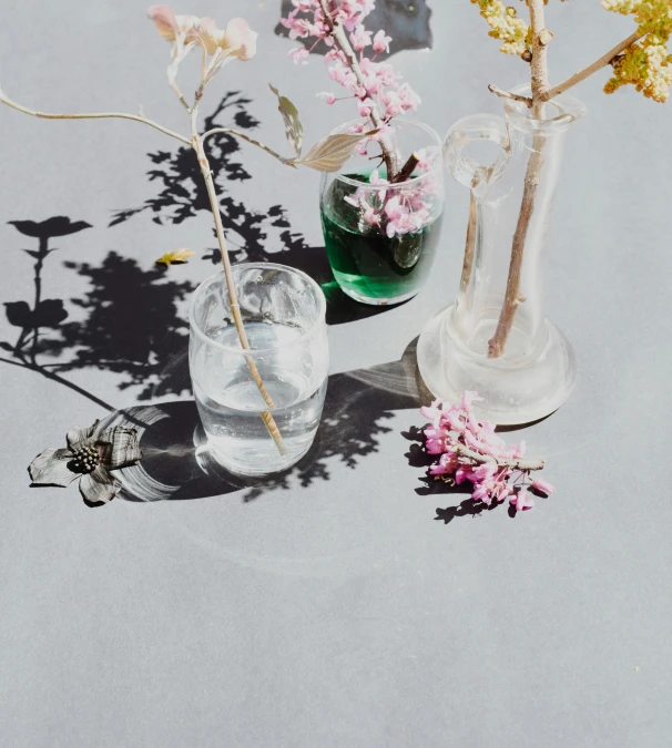 two vases and small flowers sitting on top of a table