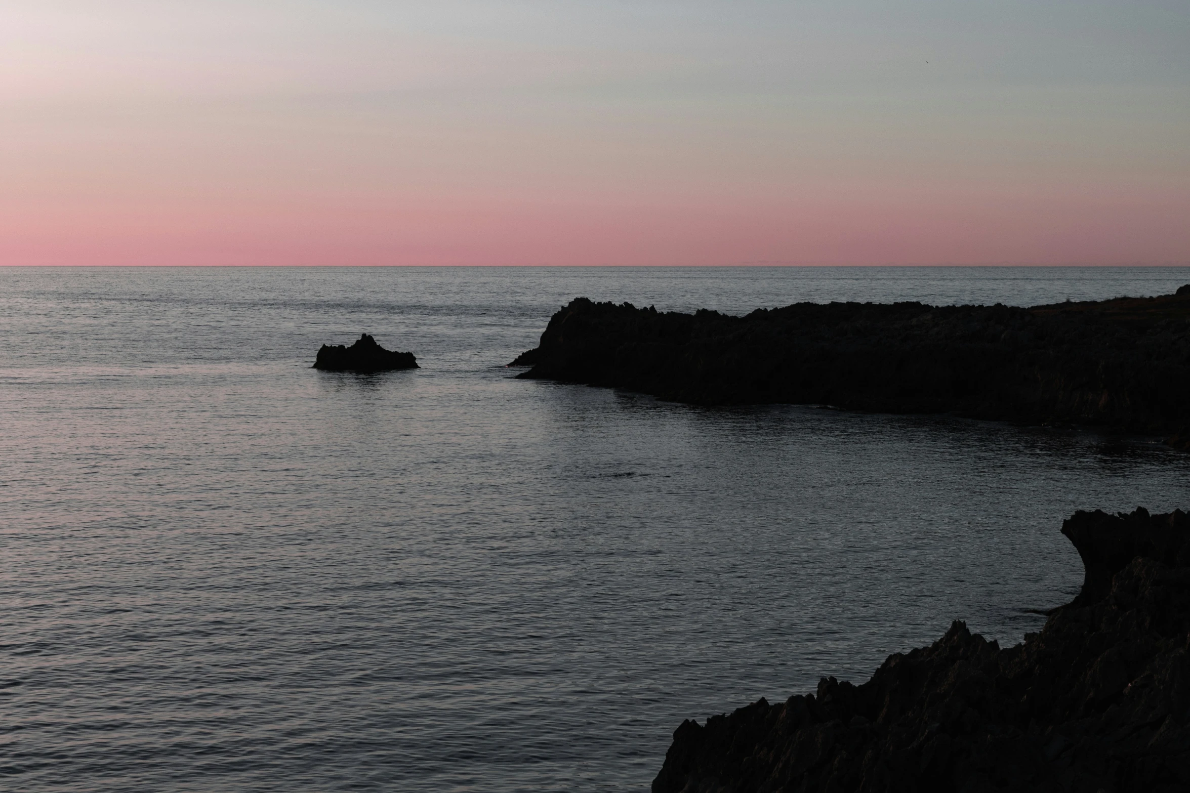 a lone boat on the water near a cliff