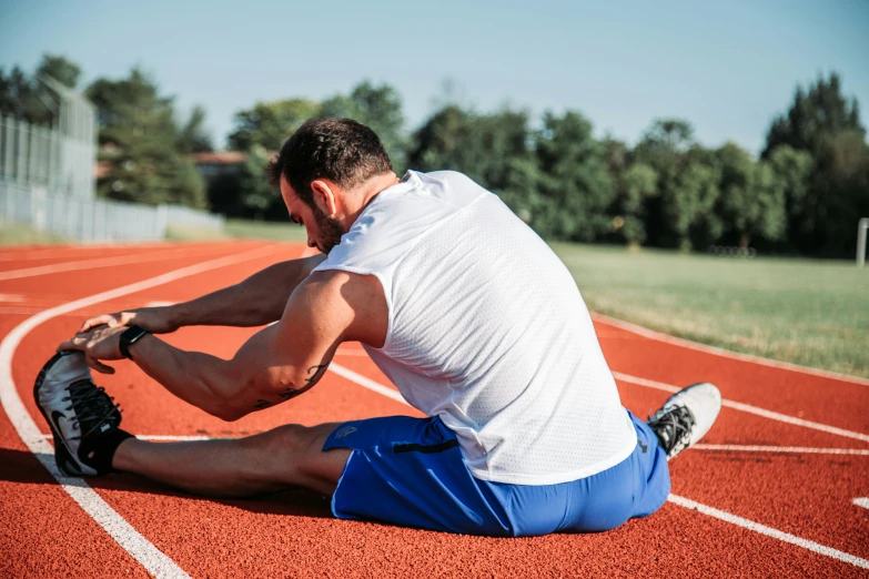 a young man sitting on the ground in a track