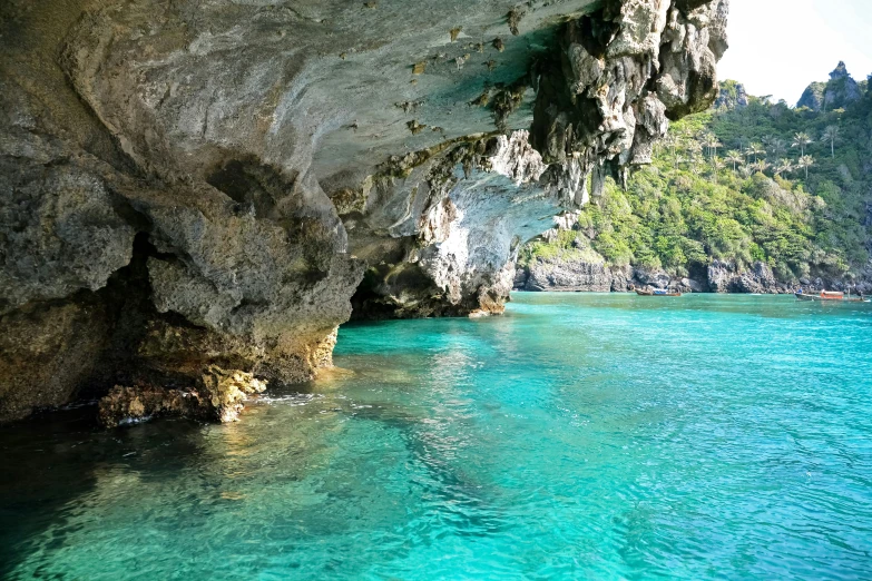 clear blue water is swimming under a cliff