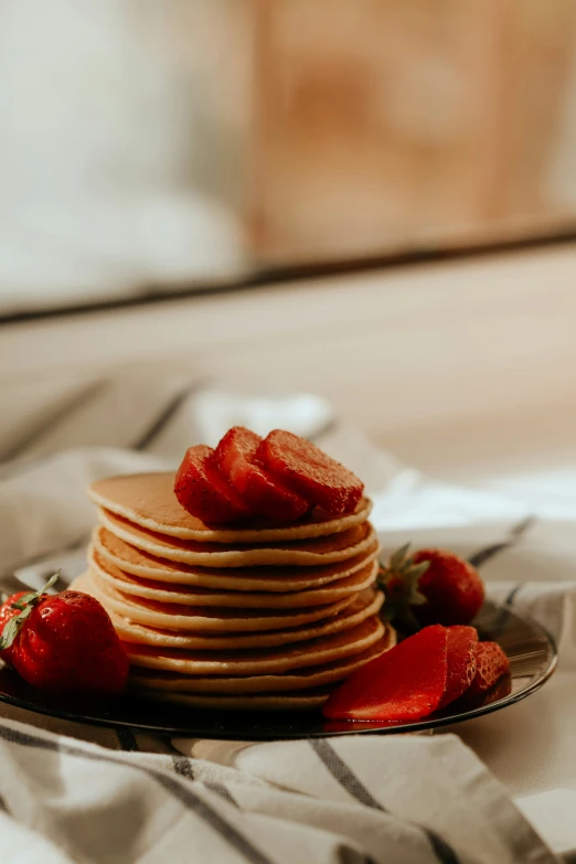 pancakes with strawberries on top served on a plate