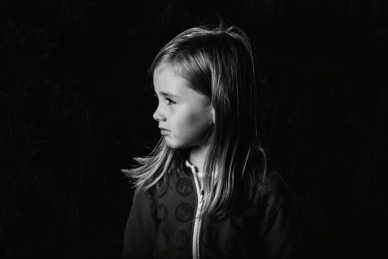 a little girl standing in front of a black background