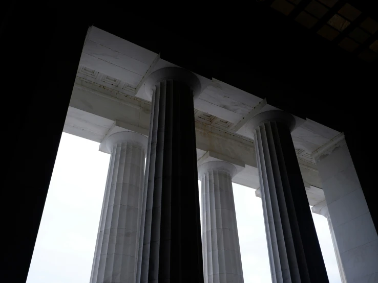 three pillar in front of a cloudy sky and window