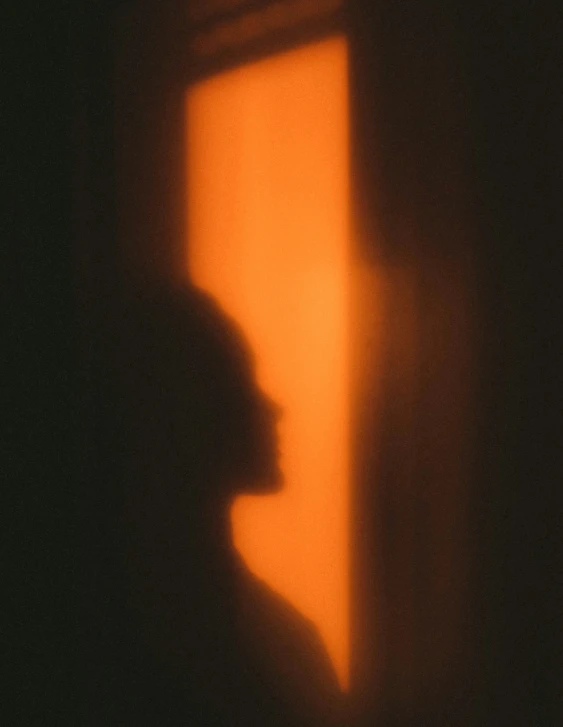 silhouette of a person in front of an open window, and a shadow on the wall