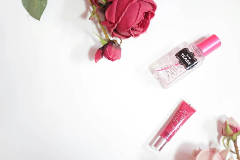 roses on white background with bottles of makeup and lip balm