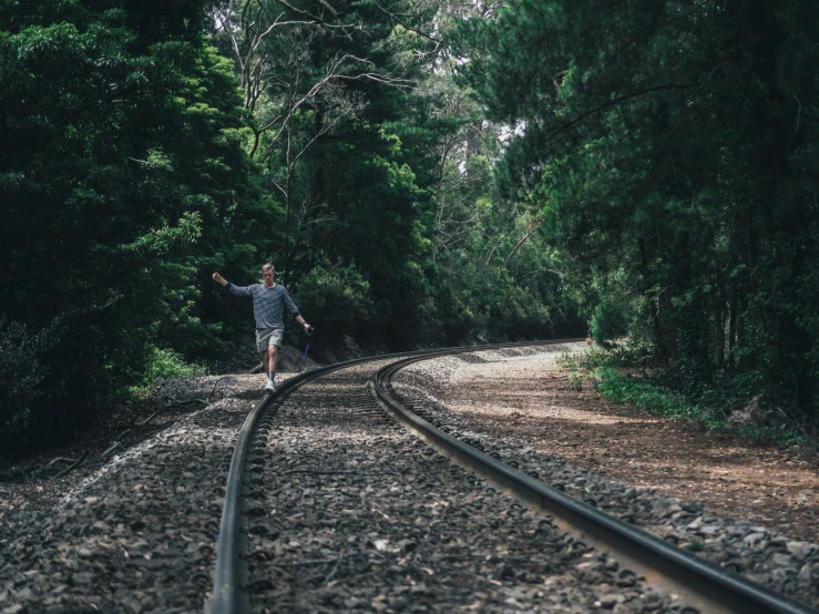 a man in striped shirt running across railroad tracks