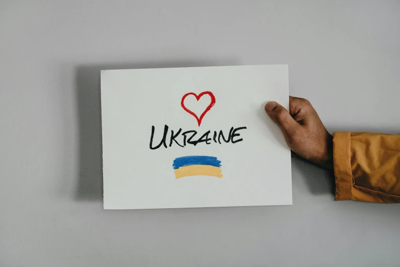 someone holds a piece of paper with the text ukraine on it