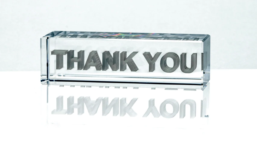 a clear rectangular sign with the words thank you written on it