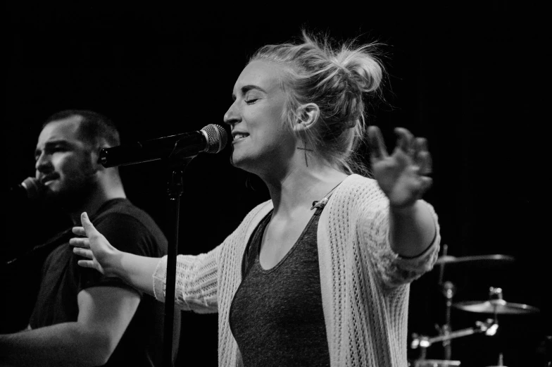 a man and woman on stage one is singing into a microphone