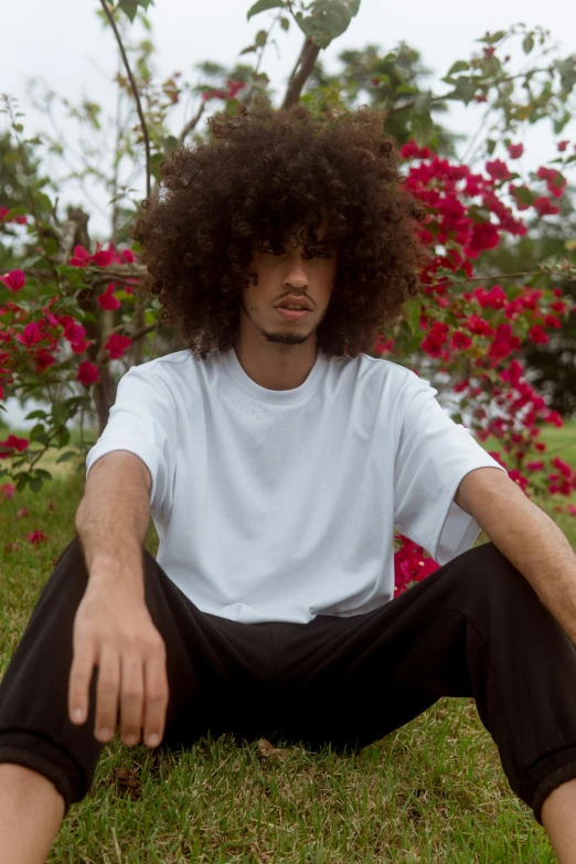 a man with long hair sitting on grass