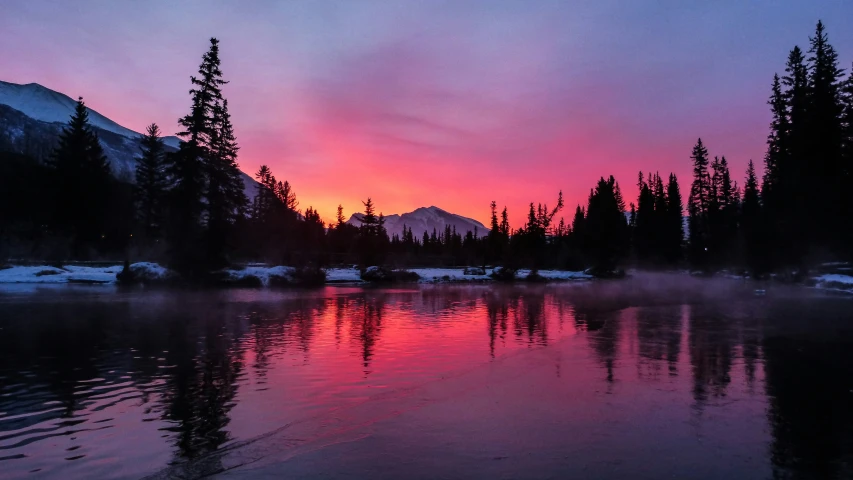 a misty mountain river and trees in the snow