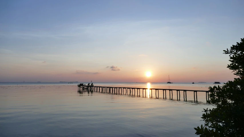 the sun rises over water at the beach