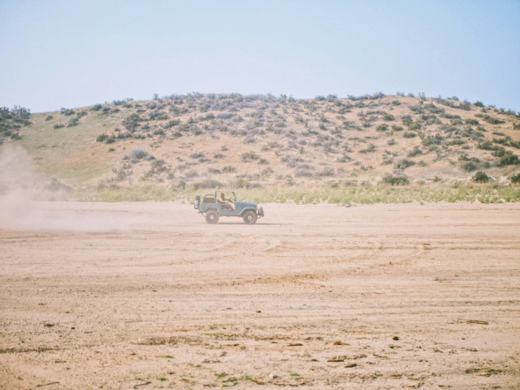 a truck with a small tractor behind it in an open plain