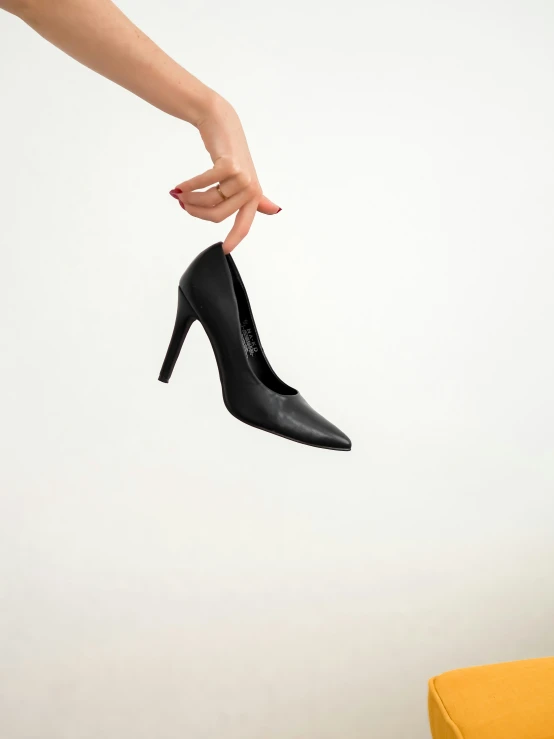 a woman's hand is holding a high heeled shoe