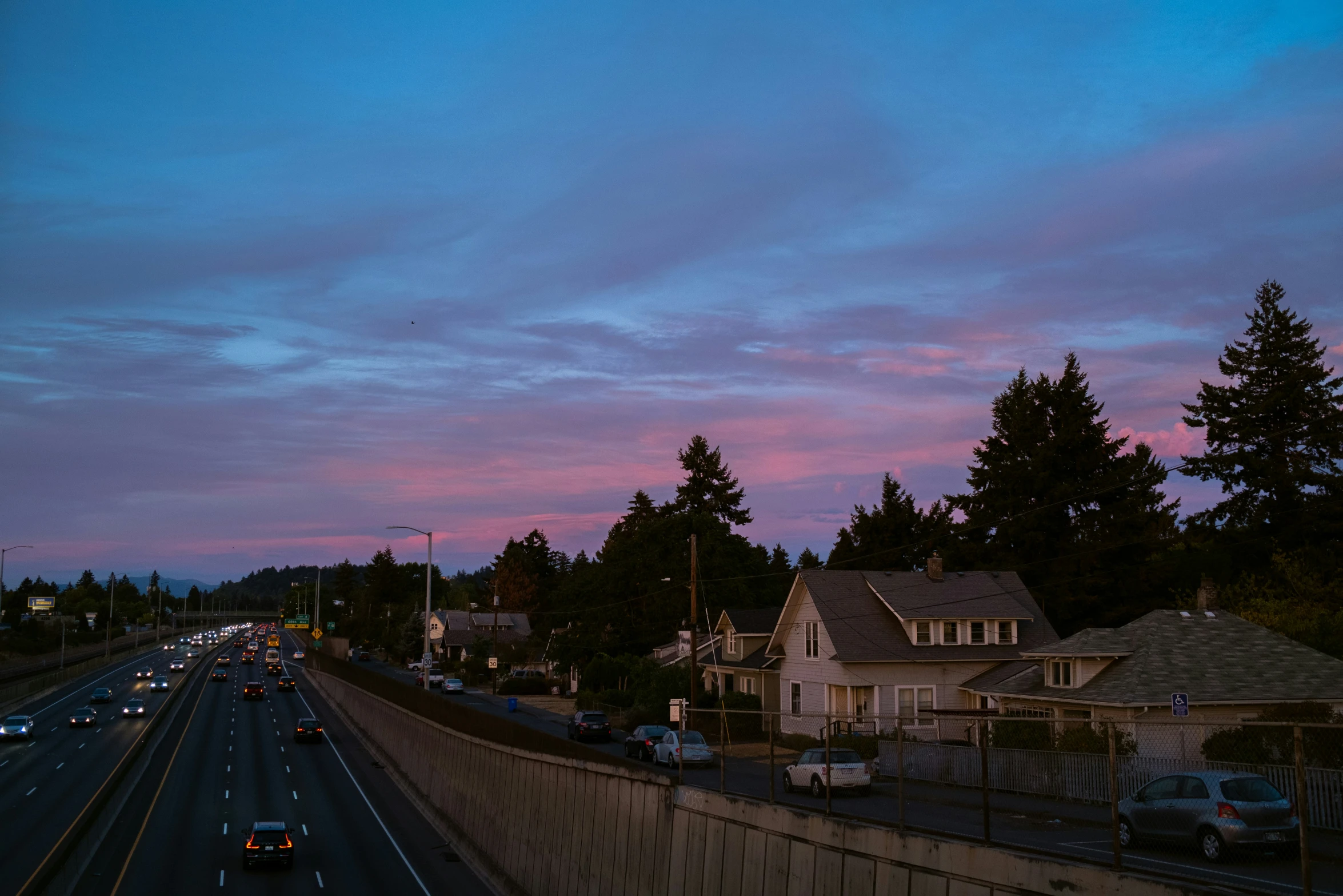 a pink sky above a freeway and houses