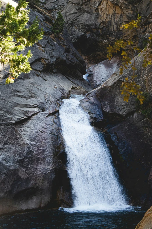 the waterfall is next to the rocks and trees