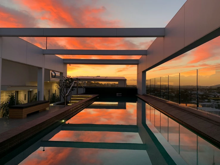 a pool is seen with a sunset behind it