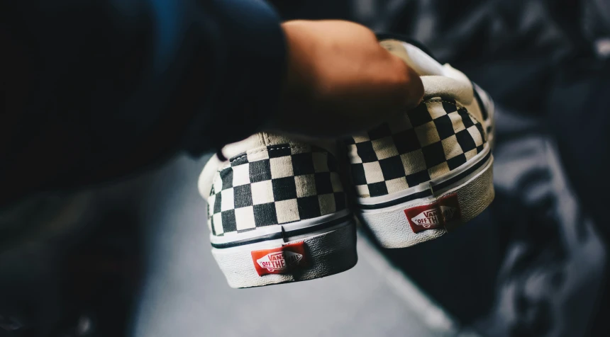 a person wearing a pair of vans checkered shoes