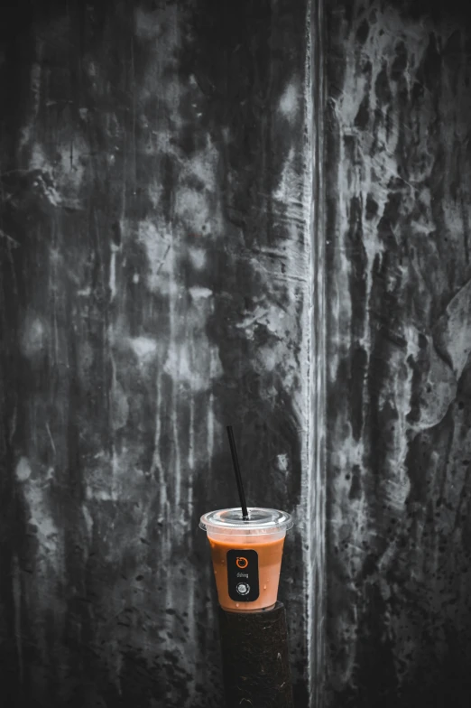 an iced beverage with straws on it next to a concrete wall