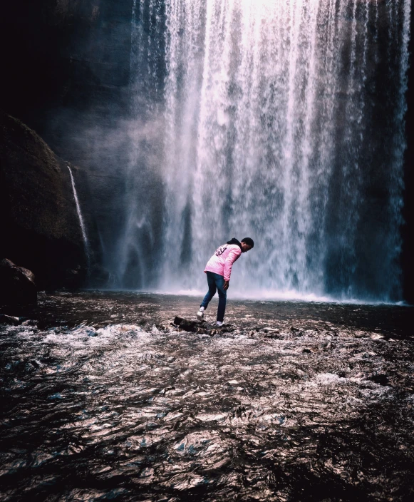 a woman riding a skateboard next to a large waterfall