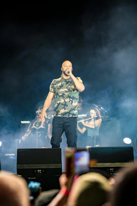 man with microphone on stage with smoke behind him