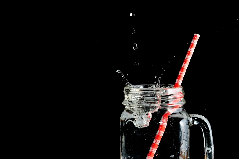 a glass of soda with a straw in it on a black background