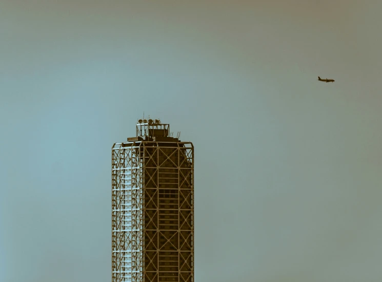 an airplane flies in front of a building under construction