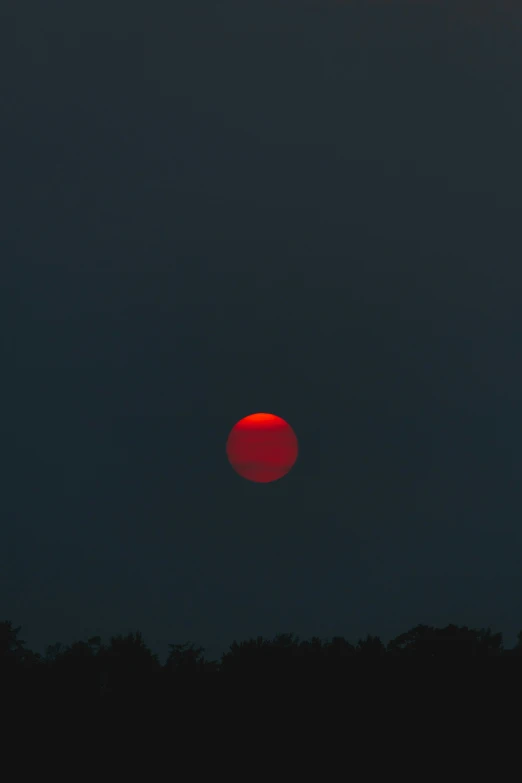 a dark sky with red sun with a very bright center