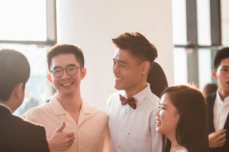 two men are smiling while one man in a white suit looks back