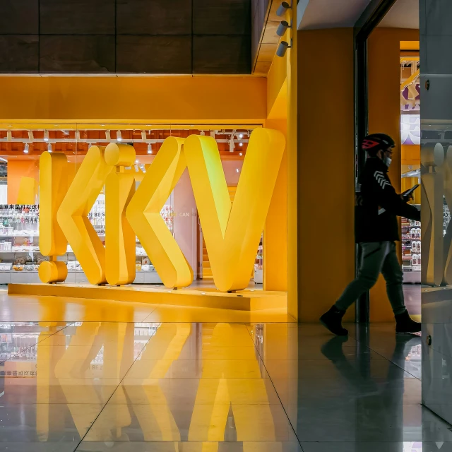 there are people walking by a tall yellow letters