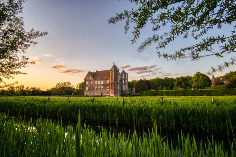 green grass with building and water with sunset in the background