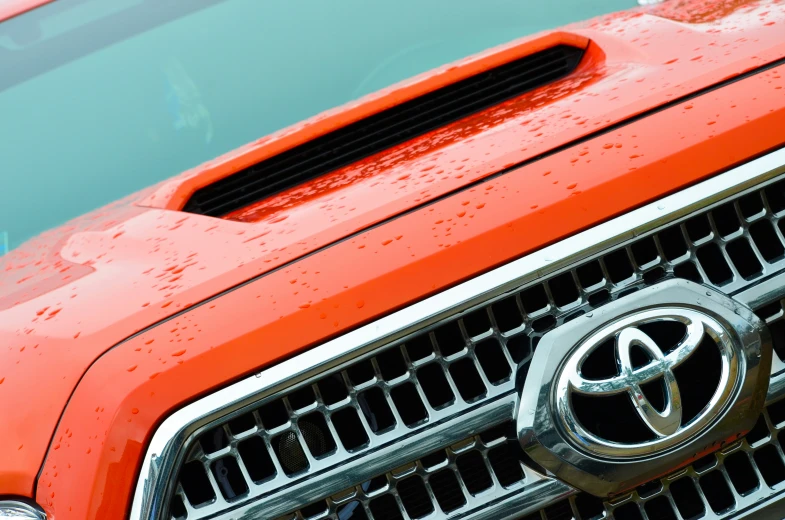 a close up view of an orange and black toyota pickup truck grill grille