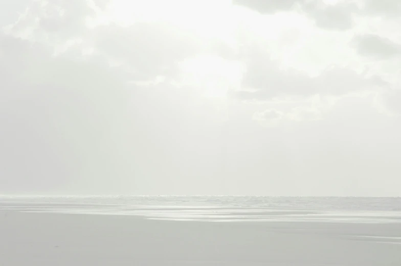 there are people walking on the beach under a bright sky