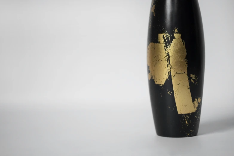 an artistic black and gold vase that is painted gold