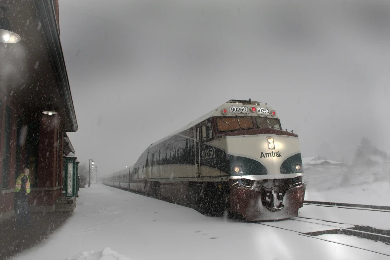 the train is driving down the tracks on a snowy day