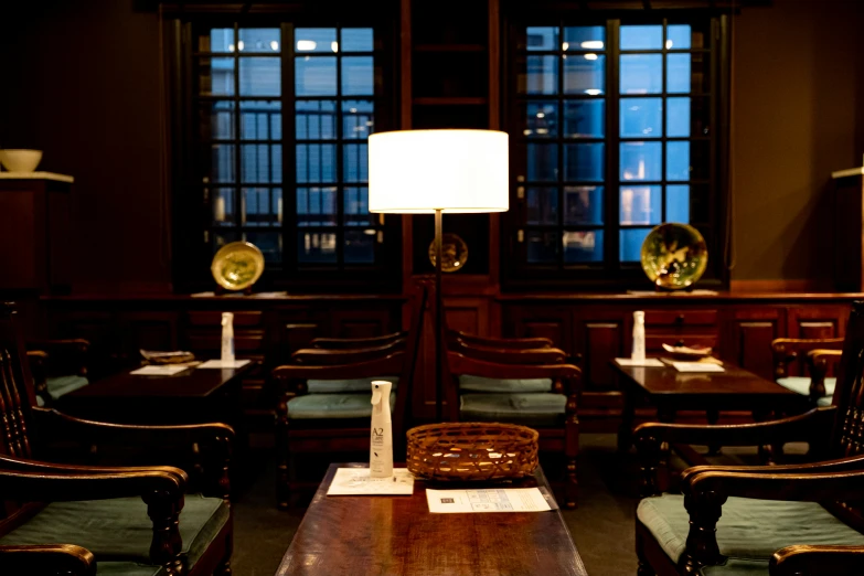 a restaurant table and chairs with a large floor lamp next to it