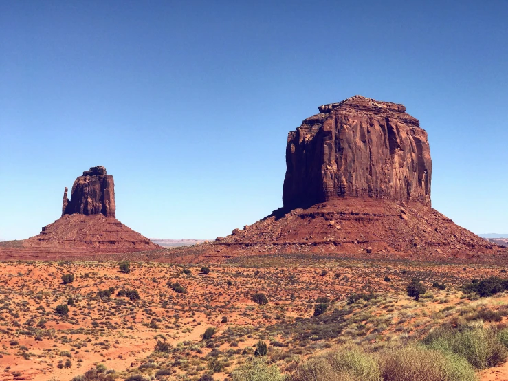 two large rock formations are shown with grass and bushes