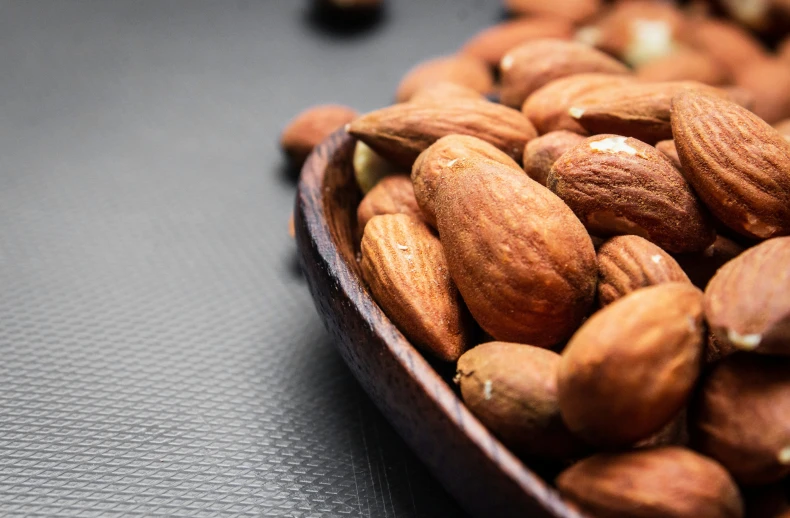 a wooden bowl filled with almonds on top of a table