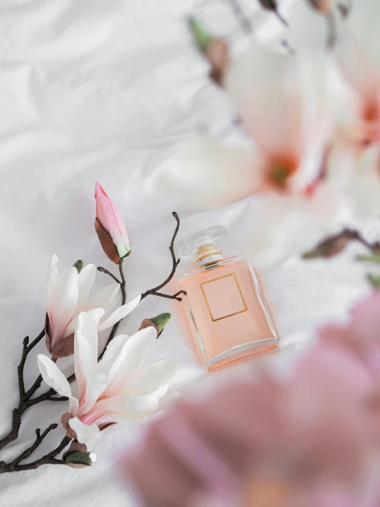 a bottle with pink liquid on a white sheet with flowers