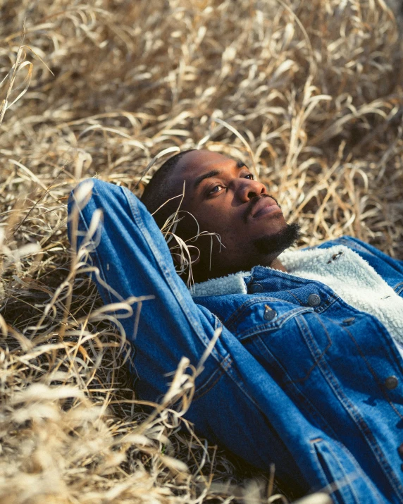 a young black man laying down in a wheat field