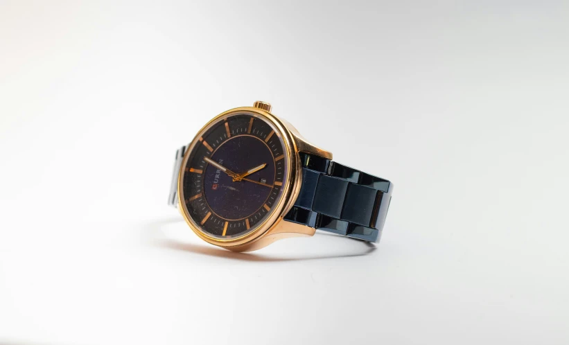 a gold watch with black face and dark blue dial