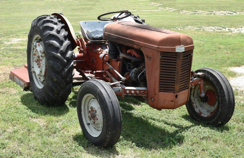 an old red tractor sitting in the middle of the field