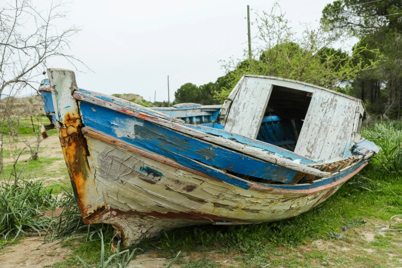 a very old rundown wooden boat lying on the ground