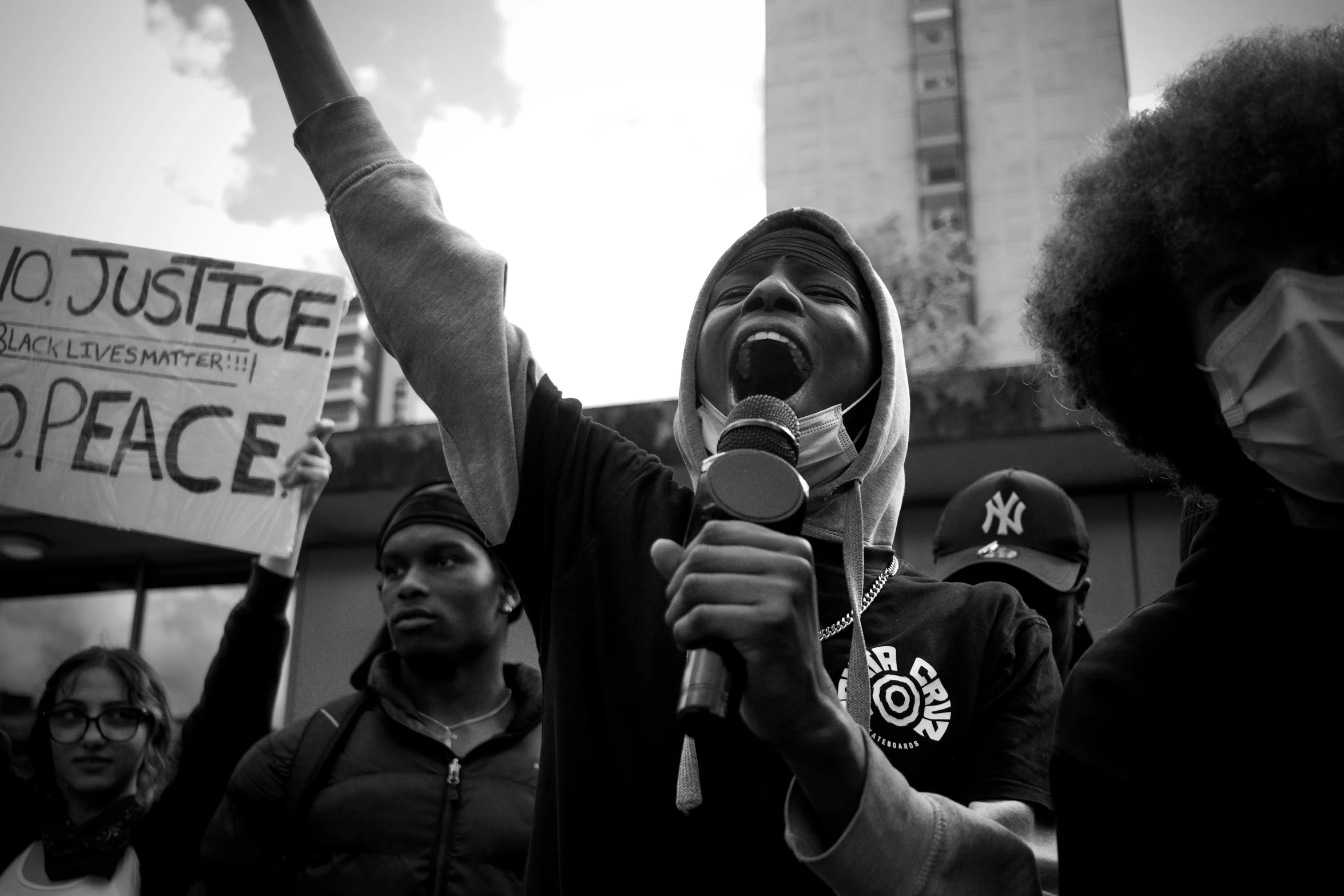 a protester in front of a large group of protesters, including a woman with a microphone